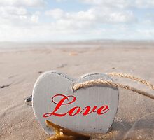 inscribed wooden love heart in the sand by morrbyte